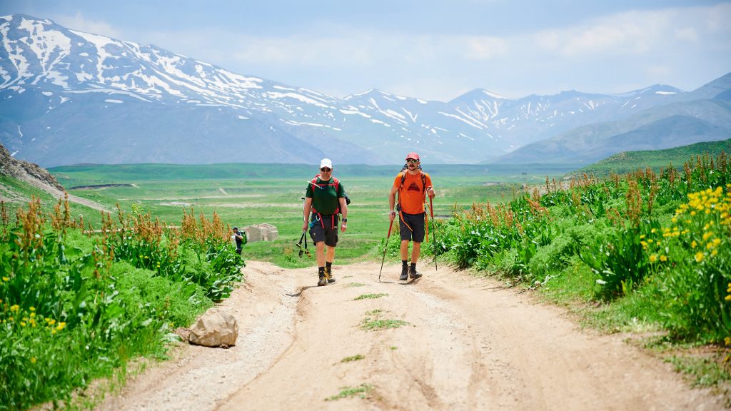 Two hikers on a gravel road in Dar valley in Iran