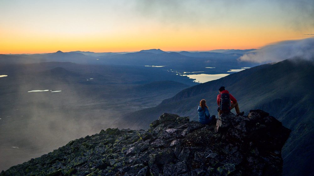 Young couple enjoy the sunset on a mountaintop in Norway