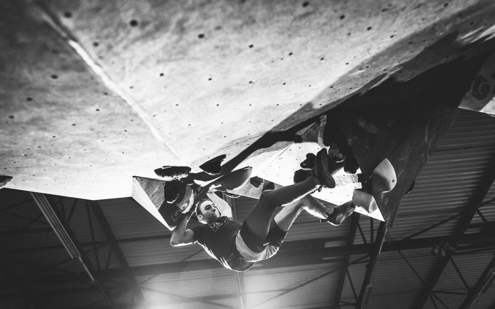 Climber climbing in a roof in an indoor bouldergym