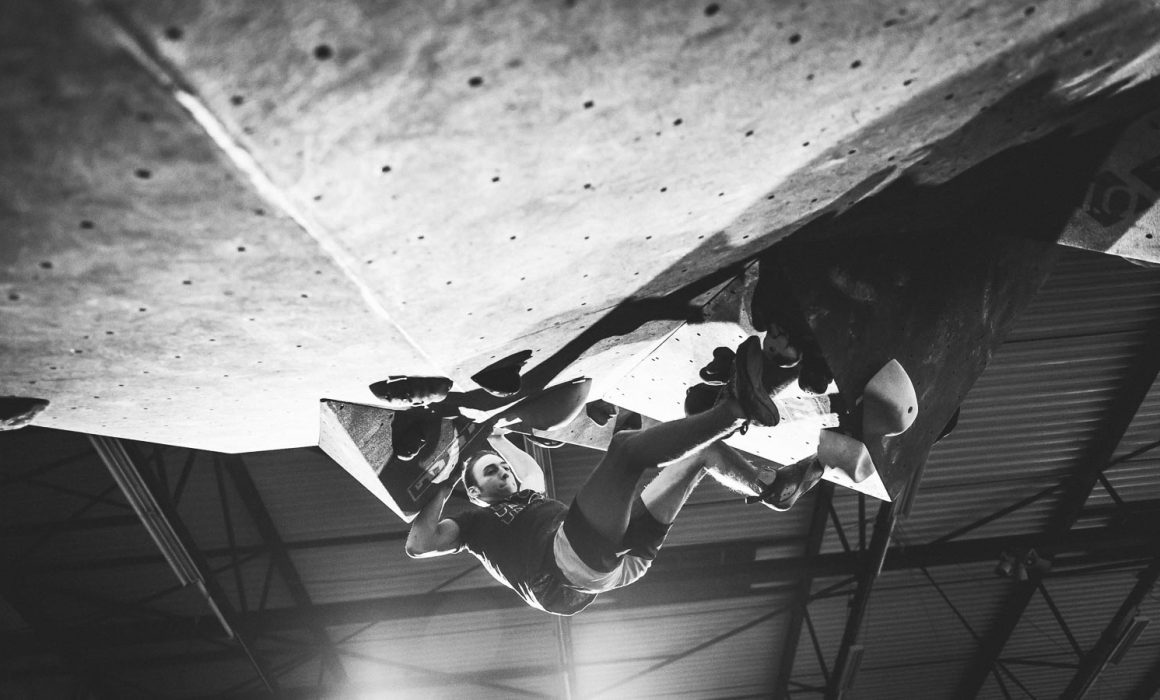 Climber climbing in a roof in an indoor bouldergym