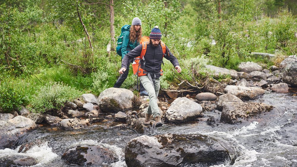Hikers crossing a wild river in Norway